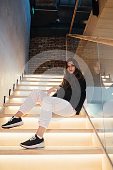 Young beautiful brunette fashion model posing on stairs.