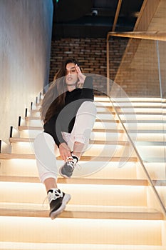 Young beautiful brunette fashion model posing on stairs.