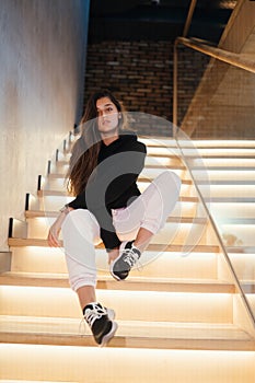 Young beautiful brunette fashion model posing on stairs.