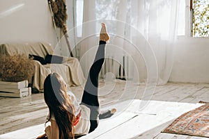 Beautiful brunette fitness woman make stretching exercises indoors at home. Staying fit and healthy