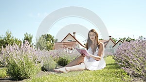 Beautiful brunette girl 25 years old sitting in a field of lavender reading a book in nature