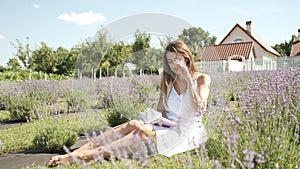 Beautiful brunette girl 25 years old sitting in a field of lavender reading a book in nature