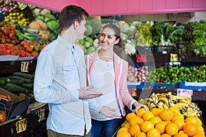 Beautiful brunette girl and boyfriend buying citruses