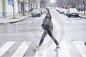 Beautiful brunette girl crosses the road on a pedestrian crossing.