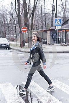 Beautiful brunette girl crosses the road on a pedestrian crossing.