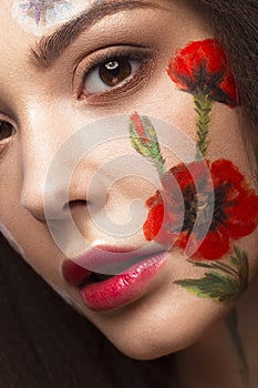 Beautiful brunette girl with curls and a floral pattern on the face. Beauty flowers.