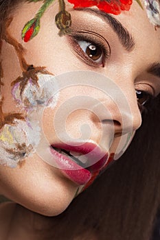 Beautiful brunette girl with curls and a floral pattern on the face. Beauty flowers.