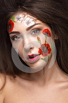 Beautiful brunette girl with curls and a floral pattern on the face. Beauty flowers.