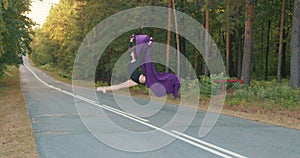 beautiful brunette girl dancer jumping on the road.