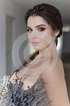 Beautiful brunette girl in elegant dress with long train with lavender flowers