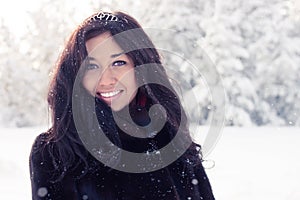 Beautiful brunette girl in a fur coat on background of a winter forest