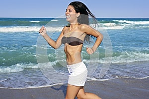 Beautiful brunette girl jumping on the beach