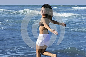 Beautiful brunette girl jumping on the beach