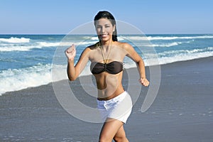 Beautiful brunette girl jumping on the beach