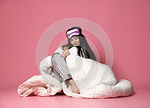 Beautiful brunette girl just woke up with soft blanket and sleepy mask bandage for sleep happy smiling on pink