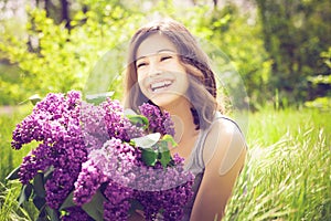 Beautiful brunette girl with a lilac flowers relaxing and enjoying life in nature. Outdoor shot. Copyspace