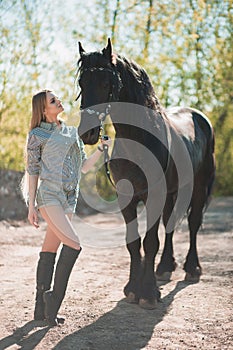 Beautiful brunette girl with long hair posing with a red horse in forest