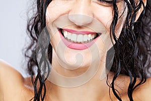 Beautiful brunette girl with long wet hair, abstract closeup studio portrait. Smiling face expression. Big smile with white teeth