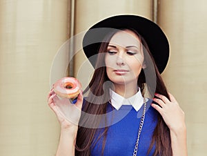 Beautiful brunette girl looking for a tasty pink donut