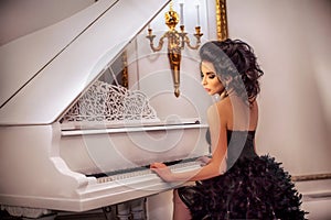 A beautiful brunette girl in the Palace sits at the piano.