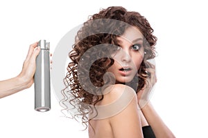 Beautiful brunette girl with a perfectly curly hair with spray bottle, and classic make-up. Beauty face.