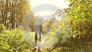 Beautiful brunette girl with ponytail running through autumn forest. Warm sunny day, blazing sun. Super slow motion