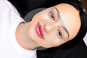 Beautiful brunette girl after the procedure of permanent makeup of the lips work after different lips made using a tattoo machine