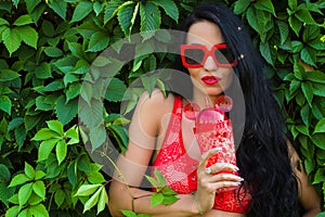 Beautiful brunette girl in red glasses with bottle of water