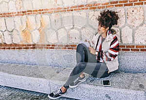 Beautiful brunette girl sitting on a stone bench, thinks as she writes in her notebook, on a cold day