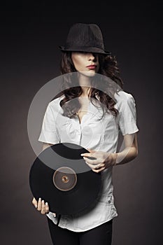 Beautiful brunette girl with vinyls on dark background