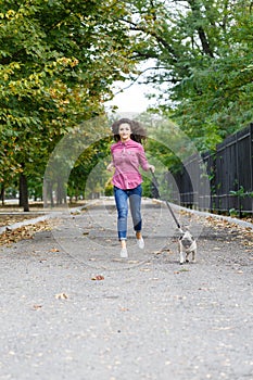 Beautiful brunette girl walking with dog in the park. Animal concept.