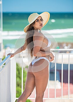 Beautiful brunette girl in a white bathing suit.Portrait of professional swimwear model posing provocatively outdoor
