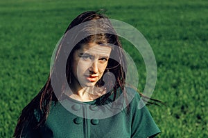 Beautiful brunette girl in windy green field, sunny springtime,