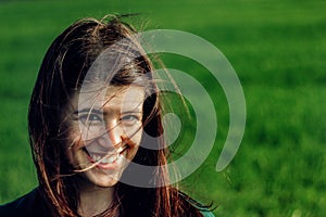 Beautiful brunette girl in windy green field, sunny springtime,