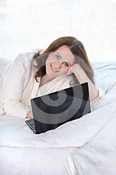 Beautiful girl. Work at home. Black notebook. White Bed