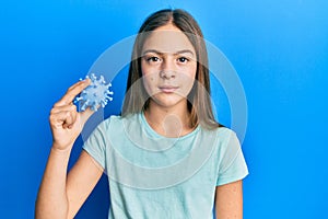 Beautiful brunette little girl holding virus toy thinking attitude and sober expression looking self confident