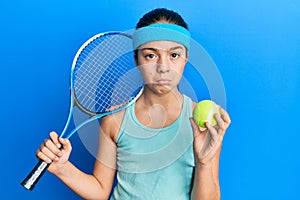 Beautiful brunette little girl playing tennis holding racket and ball depressed and worry for distress, crying angry and afraid