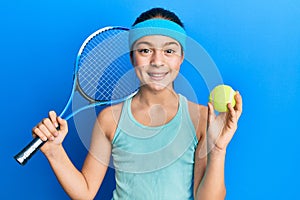 Beautiful brunette little girl playing tennis holding racket and ball smiling with a happy and cool smile on face