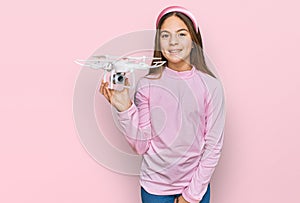 Beautiful brunette little girl using drone looking positive and happy standing and smiling with a confident smile showing teeth