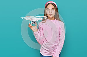 Beautiful brunette little girl using drone thinking attitude and sober expression looking self confident