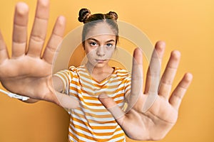 Beautiful brunette little girl wearing casual striped t shirt doing frame using hands palms and fingers, camera perspective