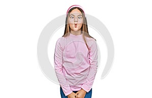Beautiful brunette little girl wearing casual turtleneck sweater making fish face with lips, crazy and comical gesture