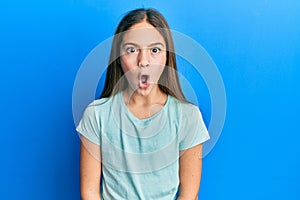 Beautiful brunette little girl wearing casual white t shirt afraid and shocked with surprise expression, fear and excited face