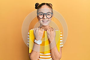 Beautiful brunette little girl wearing glasses and holding book smiling with a happy and cool smile on face