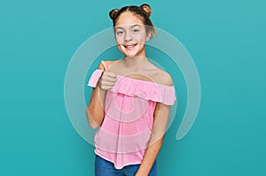 Beautiful brunette little girl wearing summer pink shirt smiling happy and positive, thumb up doing excellent and approval sign