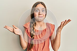 Beautiful brunette little girl wearing summer shirt clueless and confused with open arms, no idea and doubtful face