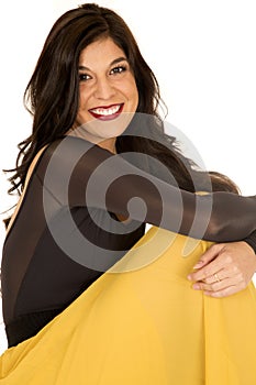 Beautiful brunette model sitting smiling wearing a yellow skirt