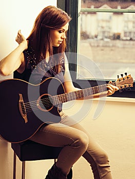 Beautiful brunette playing acoustic guitar