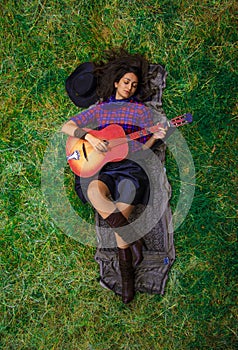 Beautiful brunette is playing the guitar and enjoying the simple life in the countryside