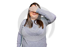 Beautiful brunette plus size woman wearing casual clothes covering eyes with hand, looking serious and sad